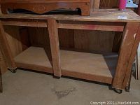 Front view of large wooden workbench with large lower shelf and sturdy construction.