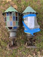 Front view of two lanterns showing multicolored stained glass panels and verdigris copper domes