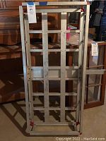 Full frontal view of metal storage rack showing grid frame, flat base, and red corner protectors indoors.