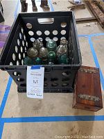 Crate containing 12 glass insulators and a wooden box with metal detail placed on the floor.