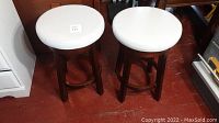 Top view of two wood bar stools with white round padded swivel seats, showing condition and color.