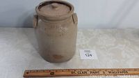 Full front view of the antique stoneware lidded crock placed next to a ruler showing approximately 9 inches in height.