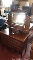 Front view of the walnut dresser showing the beveled mirror, drawer below mirror, and three drawers at the base with metal handles.