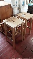 Two maple Ikea bar stools side by side showing overall construction and height with a wooden ruler for scale, photo taken to capture lot contents and size.
