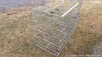 Large metal wire dog cage set up outdoors on grass, showing full size and structure