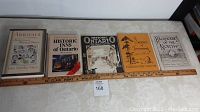 Full view of six Ontario-related history and travel books laid out on a surface below a ruler for scale.