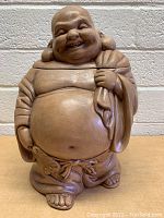 Front view of ceramic Buddha cookie jar with smiling face and big belly, lid on.