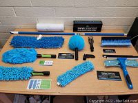 Overview of cleaning tools including microfiber mop heads, dusters, squeegees, lint roller, and extension poles all arranged on a table showing the full set.