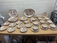 Various Barkwood pattern dishes arranged including plates, bowls, and cups on a wood tabletop against a light wall.