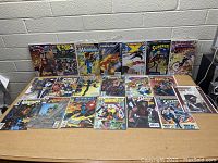 Wide view of 18 comic books arranged on table, featuring superheroes from DC and Marvel