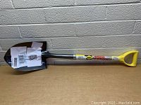 Side view of Nupla Ergo Power heavy duty shovel with yellow D-handle and steel blade showing label details.