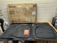 Set of Motor Trend Deep Dish Heavy Duty Floor Mats displayed on table with original packaging box behind them.