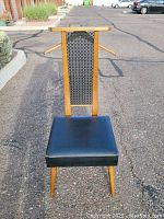 Front view of the vintage men's butler chair showing wooden frame, black vinyl seat and valet top with hanger arms.