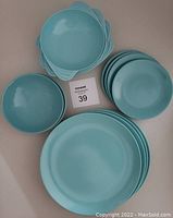 Top view of all items arranged showing 4 handled bowls, 4 dinner plates, and stacked smaller bowls.