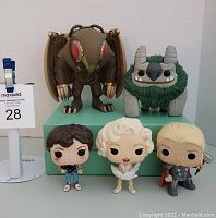 Front view of 5 loose Funko Pop figures standing on green platform showing Thor, Marilyn Monroe, brown-haired female, winged insect, and green horned creature