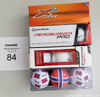 Photo of packaged golf balls stacked showing TaylorMade Aeroburner Pro, Callaway X2 Hot, Pinnacle, and Norwegian flag golf balls.