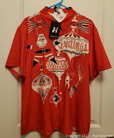 Front view of red short sleeve Christmas shirt featuring Santa and holiday ornament graphics, button down with collar, tag attached