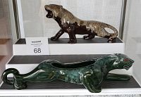 Two vintage panther pottery sculptures, green crouching planter panther and brown standing roaring panther, displayed on a shelf.
