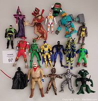 Front view of 18 assorted action figures with varied sizes and colors, arranged in orderly rows on a gray surface.