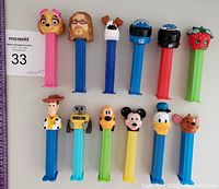 Lot of 12 loose PEZ candy dispensers with various character heads arranged for identification and condition check.