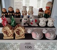 Front view of various themed salt and pepper shakers arranged on two rows including figurines of monks, cartoon chefs, Native American figure, parrots, and animal shapes.