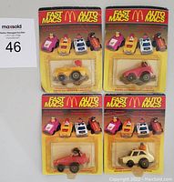Front view of four McDonald's Fast Macs branded toy cars in original blister packaging, showing some wear and blister lifting.