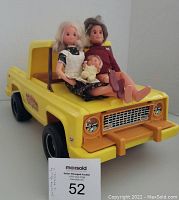 Mother, father and baby dolls seated on the yellow toy truck