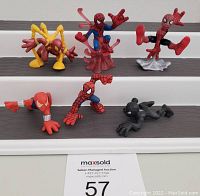 Photo showing six Spider-Man themed Super Hero Squad figures arranged on stair steps, various poses and colors including yellow, red, blue, black, and silver variants.