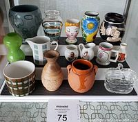 Full view of all 15 assorted tiny ceramic, clay, and glass curio decorative items on shelves.