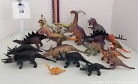Photo displaying lot of 16 toy dinosaurs arranged together showing colors and sizes