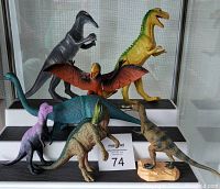 Seven vintage dinosaur figures displayed together showing various species, colors and sizes from about 4 to 6 inches tall. Condition needs cleaning.