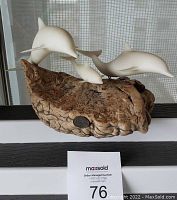 Front view of the dolphin sculpture with visible driftwood base and metal plaque.