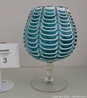 Front view of blue and white Nailsea art glass vase on a clear pedestal base against plain background, showing textured pattern.