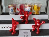 Four mini chair-shaped egg cups in packaging and three novelty red wine bottle accessories on display.