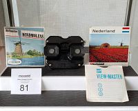 Photo of black bakelite ViewMaster viewer centered with two Holland reels on either side. Original GAF View-Master booklet in front. Includes lot number card.