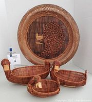 Full view of the set showing 3 nesting wicker duck baskets and a large round wicker wall peacock decorative piece.