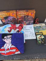 Full lot items including puzzles, throw blanket, beach towel, action figure, VHS, colouring book, and building cards laid out on table