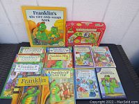 Top view of the lot featuring 7 Franklin the Turtle paperback books, Franklin's Big Lift-And-Learn interactive book, Franklin DVDs, and boxed dominoes set