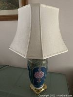 Full view of large pottery table lamp with cream hexagonal fabric shade, placed on table.