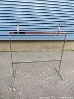 Full frontal view of the metal clothing rack showing the removable horizontal hat extension rods on the top rail.