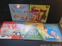 Seven vintage LP record albums arranged upright against a black background displaying their colorful cover art including Disney and AA Milne titles.