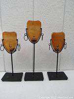 Front view of all three yellow glass and metal figural candleholders displayed against wall, showing full height differences and features.