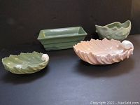 Four vintage ceramic dishes displayed on a black surface - two acanthus leaf shell dishes, one rectangular ceramic dish, and one planter.