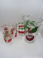 Seven-piece vintage glass set comprising two pitchers and five glasses featuring red tomato and green leaf designs.