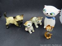 Five vintage ceramic cats displayed against neutral background, showing variety in size, color and style