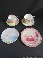 All four items in the lot displayed together including two Royal Albert teacups with saucers, one Poole Pottery plate and one Adams England souvenir plate.