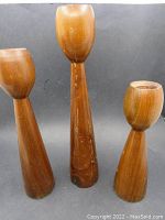Full view of the three Danish modern tulip-shaped wooden candlesticks showing different heights and visible wear.