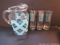 Photo of the glass pitcher with turquoise patterned wrap-around band and three clear drinking glasses with turquoise and gold Southern Comfort steamboat logos.