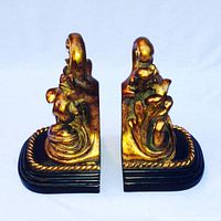 Pair of gold leaf Rococo style classical French bookends shown from front angle to display ornamental carved details and black molded bases.