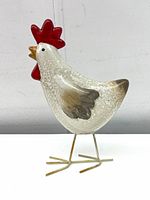 Side view of ceramic rooster figure showing the painted details and metal legs.